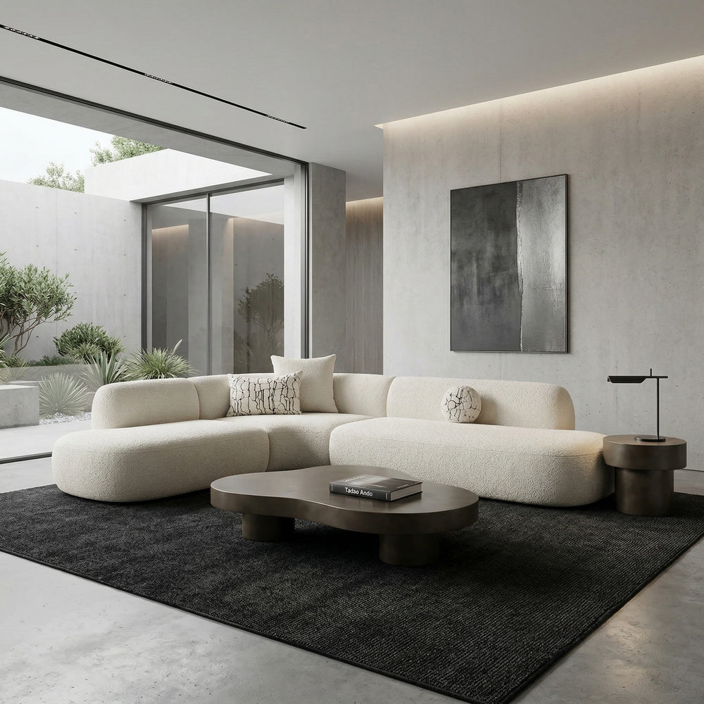 Lusso Curved Sofa in neutral fabric with plush cushions, paired with a low coffee table, modern living room setting.