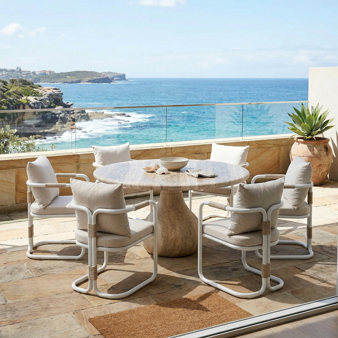 Round Aqua dining table with travertine finish, 1.5m diameter, paired with four matching chairs for outdoor dining.
