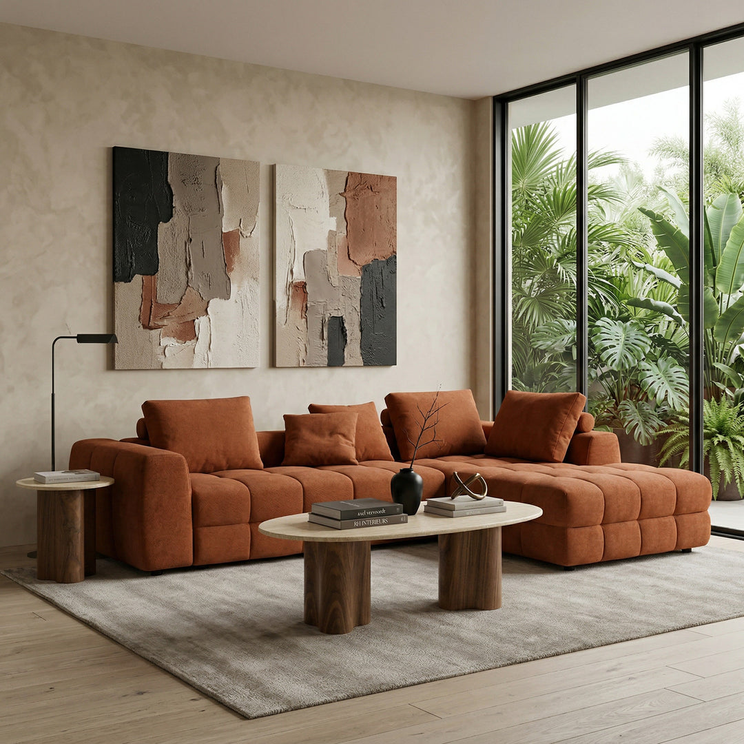Rust-colored Cuddly Modular Sofa with plush cushions, shown with matching coffee and side tables in a cozy living room setting.