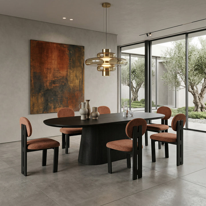 Terracotta Yarra dining chair with wooden legs, shown next to a black oak oval dining table in a modern dining room setting.