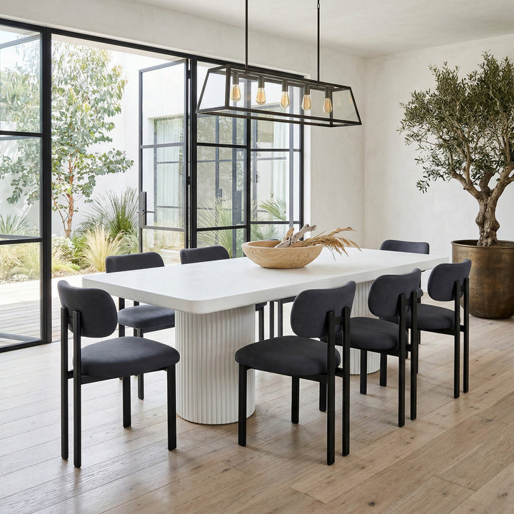 Black velvet Farinelli dining chair with sleek design, placed next to a large white rectangular dining table.