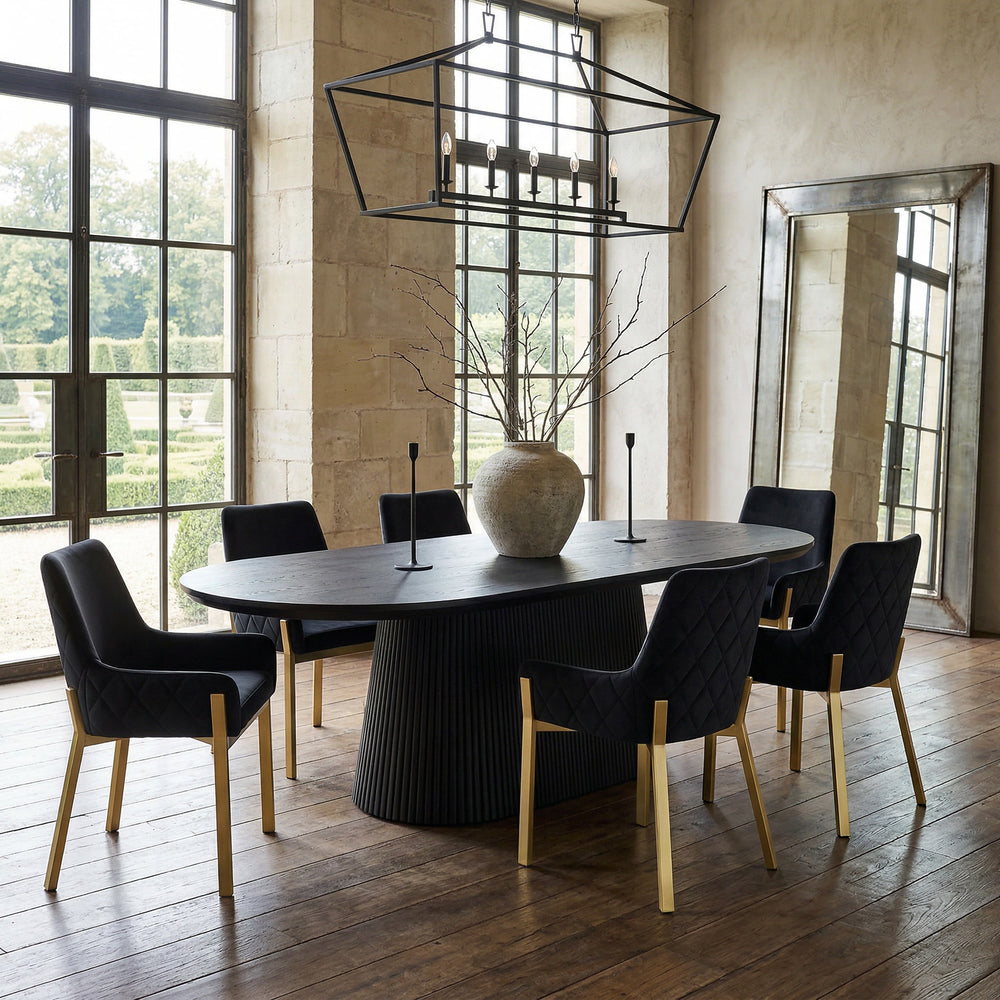 Black velvet Mateo dining chair with sleek design, shown beside a black oak oval dining table in a modern dining room setting.