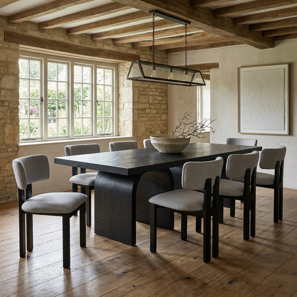Light grey Modenese dining chair with sleek design, shown next to a black oak rectangular dining table.