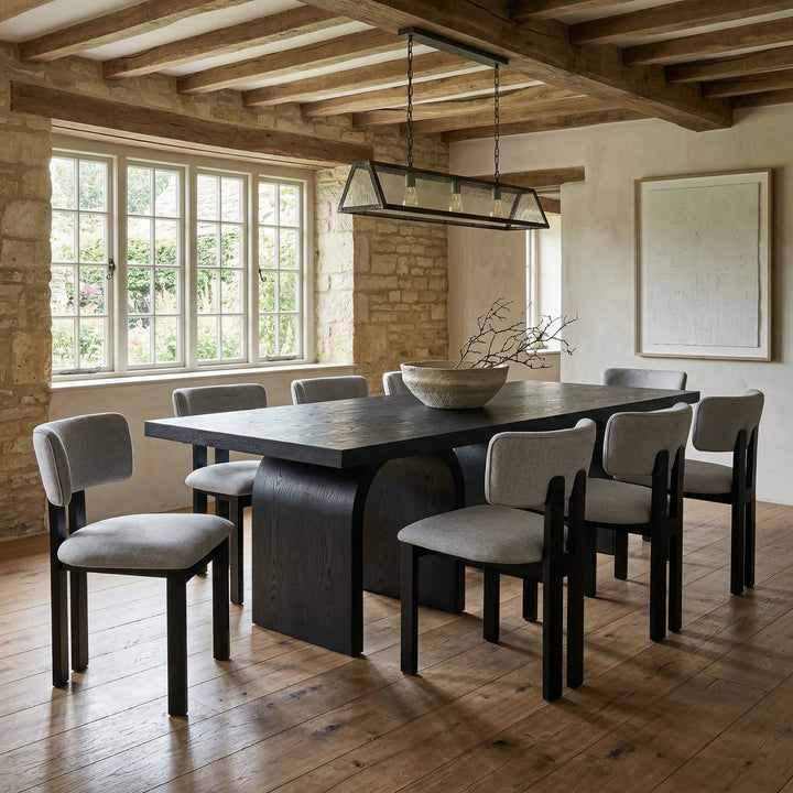 Light grey Modenese dining chair with sleek design, shown next to a black oak rectangular dining table in a modern dining room setting.