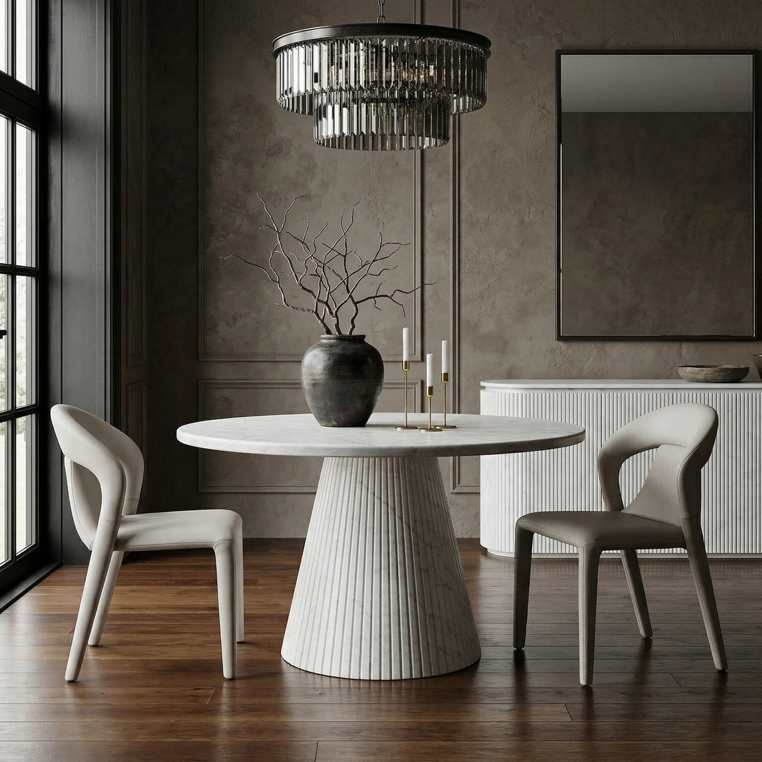 Light grey/beige leather look contour dining chair with sleek design, shown next to a round marble dining table and matching buffet.