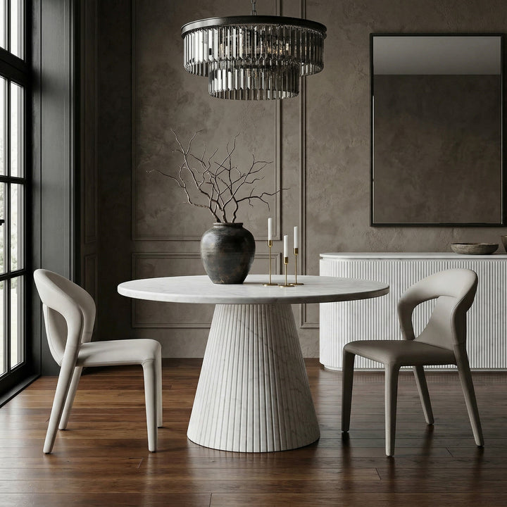 Light grey/beige leather look contour dining chair with sleek design, shown next to a round marble dining table and matching buffet.