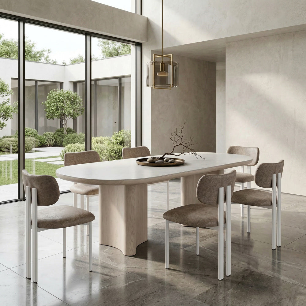 Salvatini dining chair with mushroom leather look upholstery, modern design, and wooden legs, shown next to a white wash ceramic dining table.
