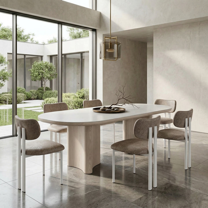 Salvatini dining chair with mushroom leather look upholstery, modern design, and wooden legs, shown next to a white wash ceramic dining table.
