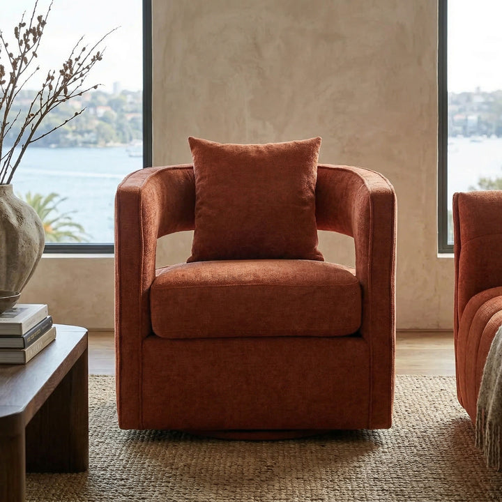 Rust-colored Rhonda swivel occasional chair with modern design, featuring a rounded back and cushioned seat in a contemporary living room setting.