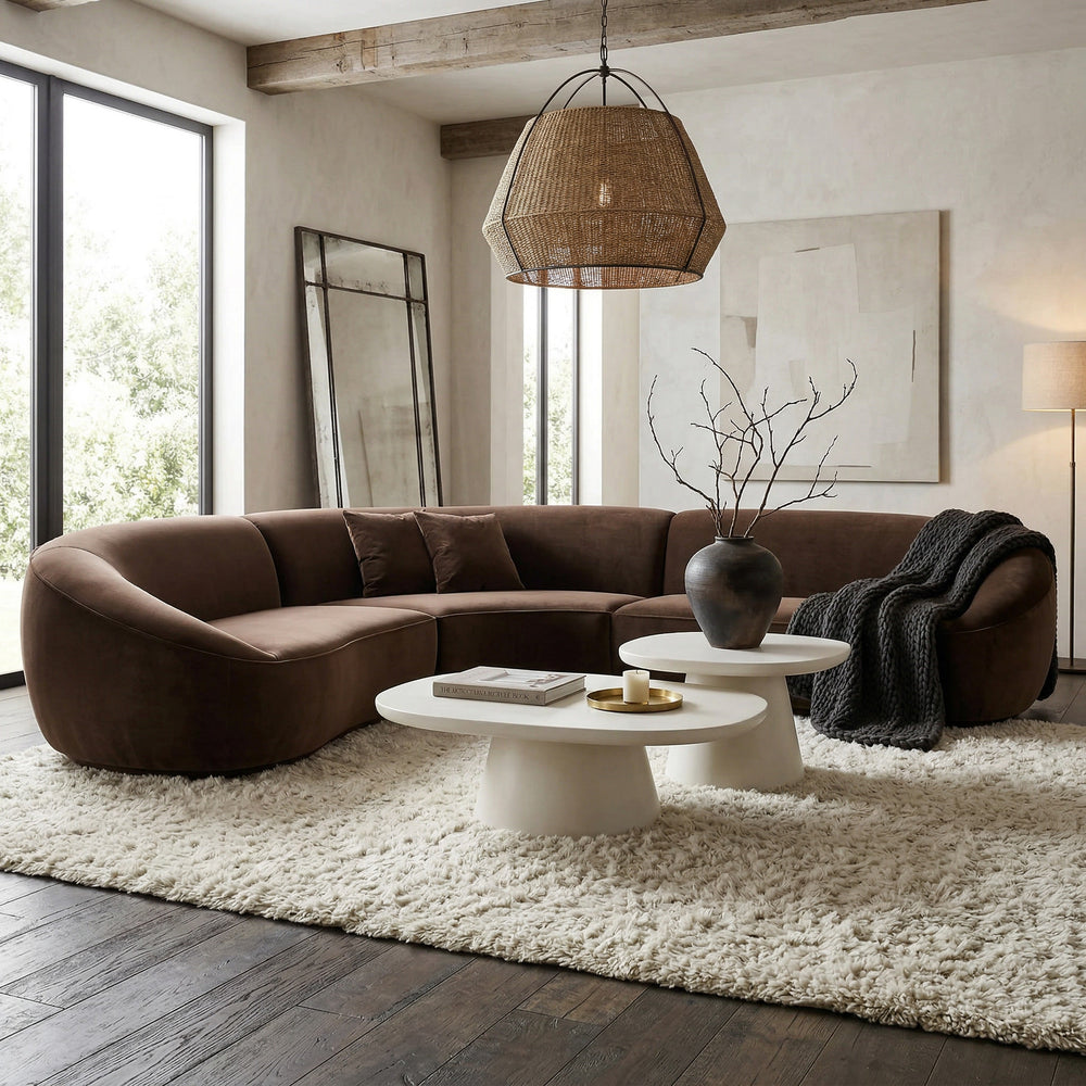 Curva Sofa featuring smooth curves and plush cushions, with two coffee tables of different heights and sizes in the background.